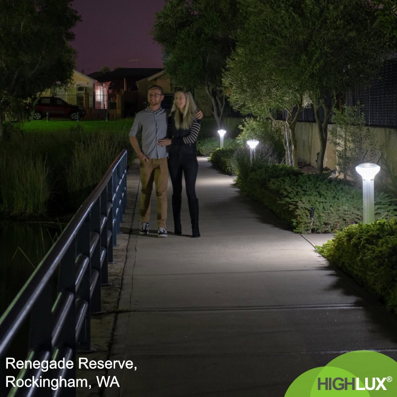 A couple walks along a well-lit path at night in Renegade Reserve, Rockingham, WA.